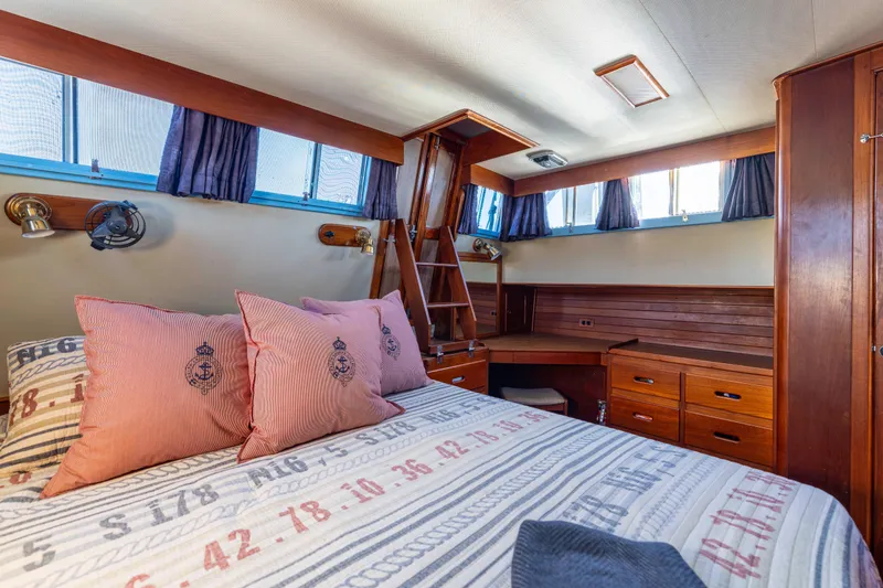 Cheers Yacht Photos Pics 1989 Grand Banks 46 Classic yacht cabin with wooden interior and nautical-themed bedding.