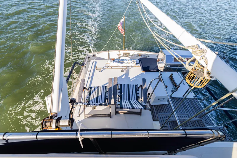 Cheers Yacht Photos Pics 1989 Grand Banks 46 Classic yacht deck with striped chairs, cruising on open water.