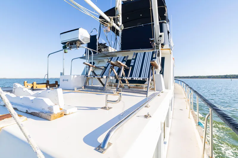 Cheers Yacht Photos Pics 1989 Grand Banks 46 Classic yacht deck with striped chairs, overlooking serene waters.