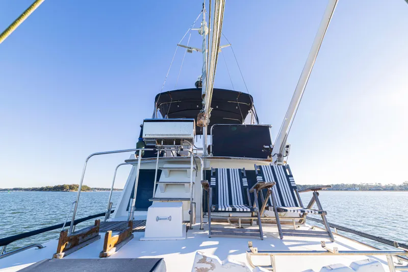 Cheers Yacht Photos Pics 1989 Grand Banks 46 Classic yacht deck with striped chairs, under clear blue sky.