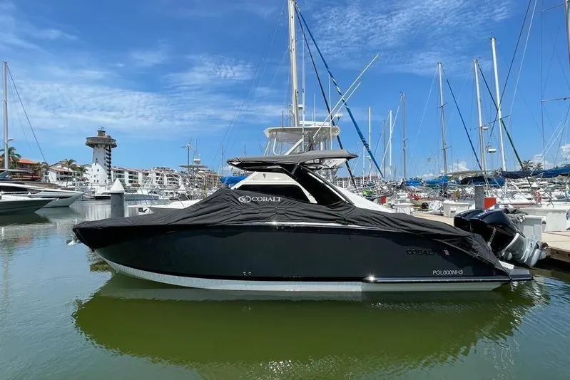 Casa - 2023 Cobalt R33 Ob @ Vallarta Yacht Photos Pics 2023 Cobalt R33 Outboard boat docked in marina, covered, with sailboats in background.