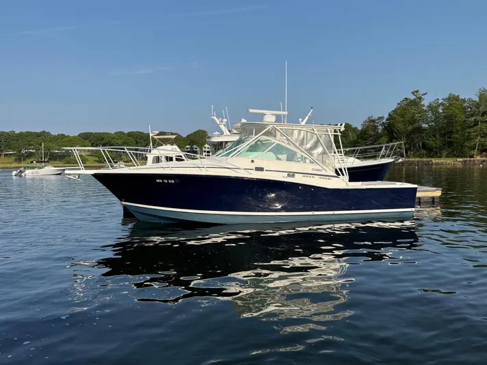 Club Car Yacht Photos Pics 1999 Cabo 31 Express boat docked on calm water, surrounded by trees.