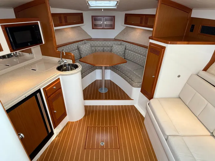 Club Car Yacht Photos Pics 1999 Cabo 31 Express interior with kitchenette, seating area, and wood accents.