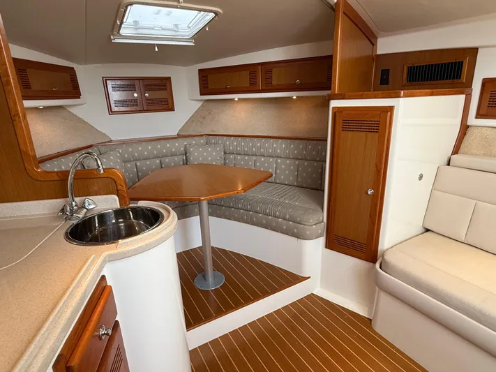 Club Car Yacht Photos Pics 1999 Cabo 31 Express interior with wood accents, cozy seating, and compact kitchenette.