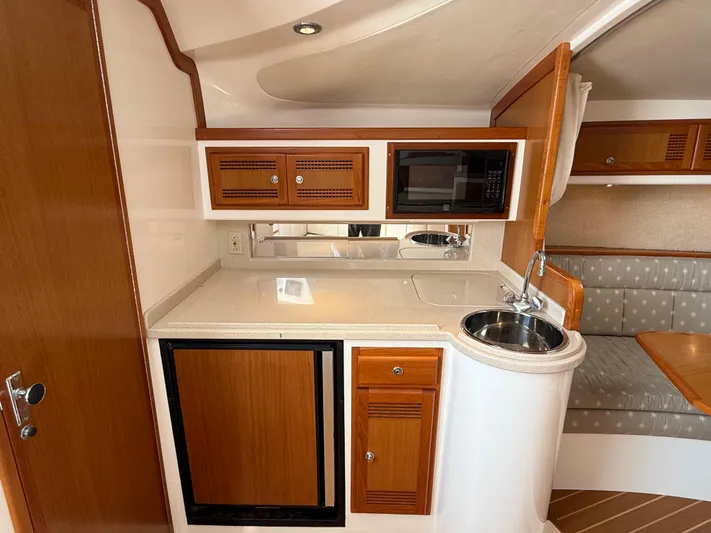 Club Car Yacht Photos Pics 1999 Cabo 31 Express yacht interior with kitchenette, featuring wood cabinets, sink, and microwave.