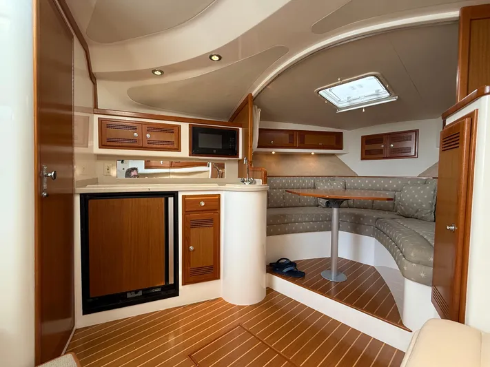 Club Car Yacht Photos Pics 1999 Cabo 31 Express yacht interior with kitchenette, seating area, and wooden cabinetry.