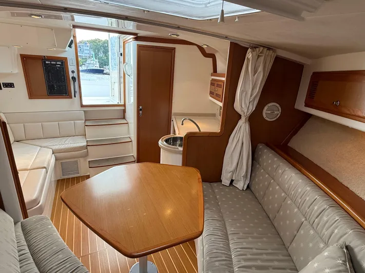 Club Car Yacht Photos Pics Interior of a 1999 Cabo 31 Express boat with seating, table, and kitchenette.