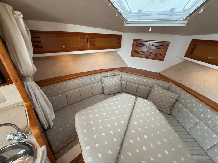 Club Car Yacht Photos Pics 1999 Cabo 31 Express cabin interior with cushioned seating and wooden storage cabinets.