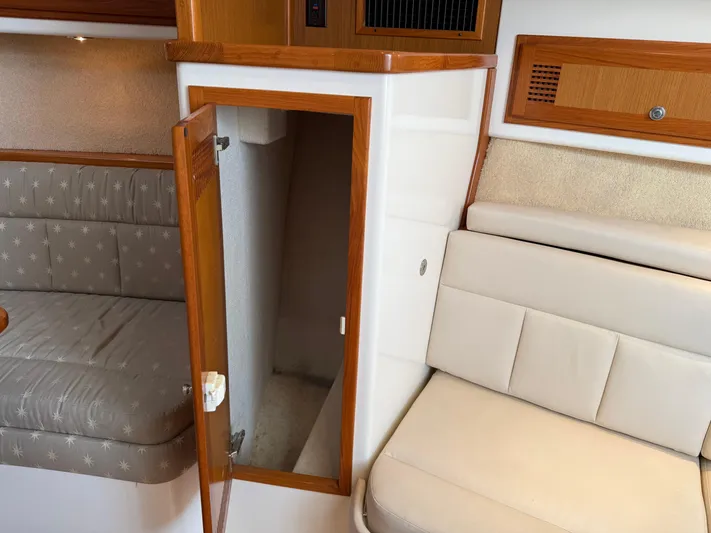 Club Car Yacht Photos Pics Interior of a 1999 Cabo 31 Express boat with open wooden cabinet and cushioned seating.