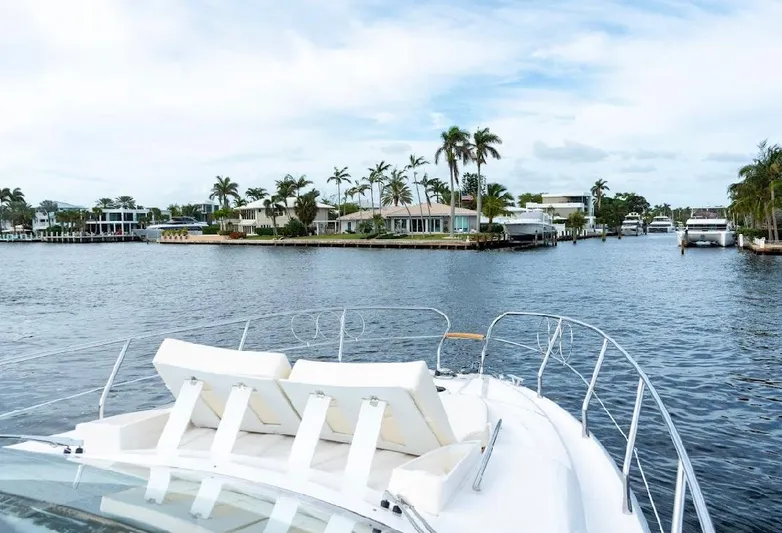  Yacht Photos Pics 2024 Sessa Marine C44 Cruiser on a scenic waterfront with palm trees and luxury homes.