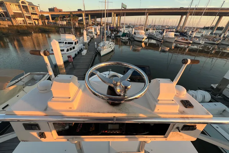 Reel Carolina II Yacht Photos Pics Helm of 2002 Out Island 38 Express Fisherman at marina, overlooking docked boats and bridge.