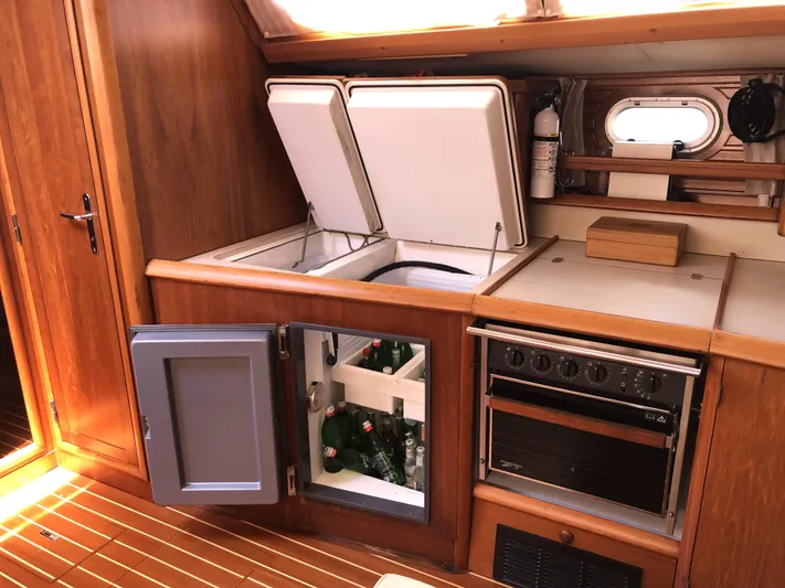 Ozymandias Yacht Photos Pics Interior of 2001 Jeanneau 45.2 yacht kitchen with fridge, stove, and wooden cabinetry.