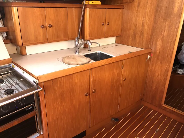 Ozymandias Yacht Photos Pics 2001 Jeanneau 45.2 yacht kitchen with wooden cabinets and sink.