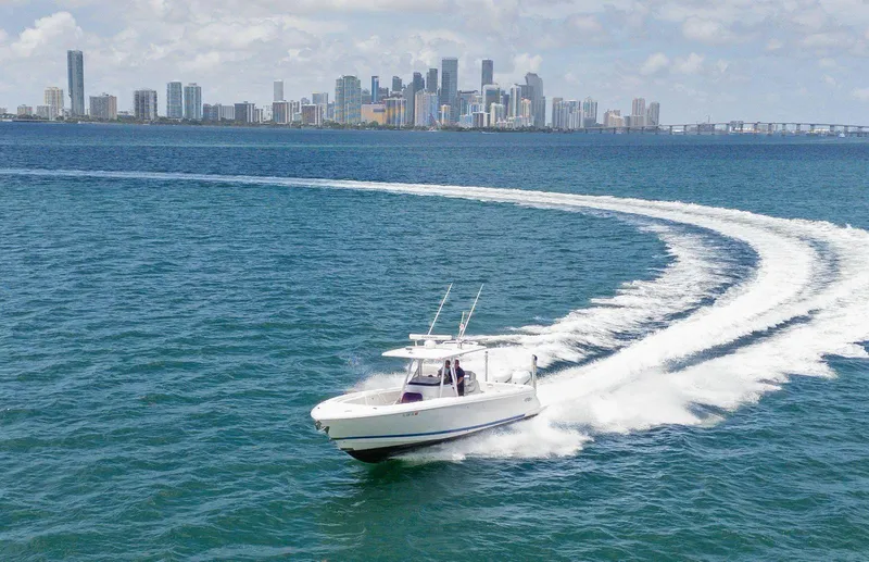  Yacht Photos Pics 2021 Intrepid 345 Nomad FE cruising on ocean with city skyline in background.
