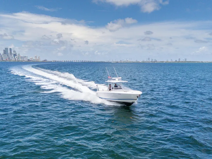  Yacht Photos Pics 2021 Intrepid 345 Nomad FE cruising on open water with city skyline in background.