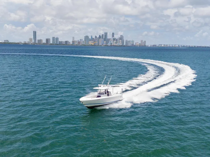  Yacht Photos Pics 2021 Intrepid 345 Nomad FE cruising near city skyline on open water.
