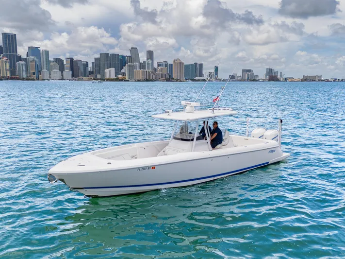  Yacht Photos Pics 2021 Intrepid 345 Nomad FE boat cruising near city skyline on a sunny day.