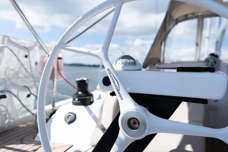 Lunar Sea Yacht Photos Pics Steering wheel of 2023 Dufour 390 sailboat with compass, under clear skies.
