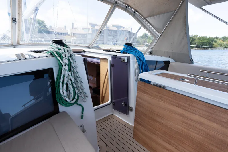 Lunar Sea Yacht Photos Pics 2023 Dufour 390 yacht cockpit with ropes and wooden accents, docked by the water.