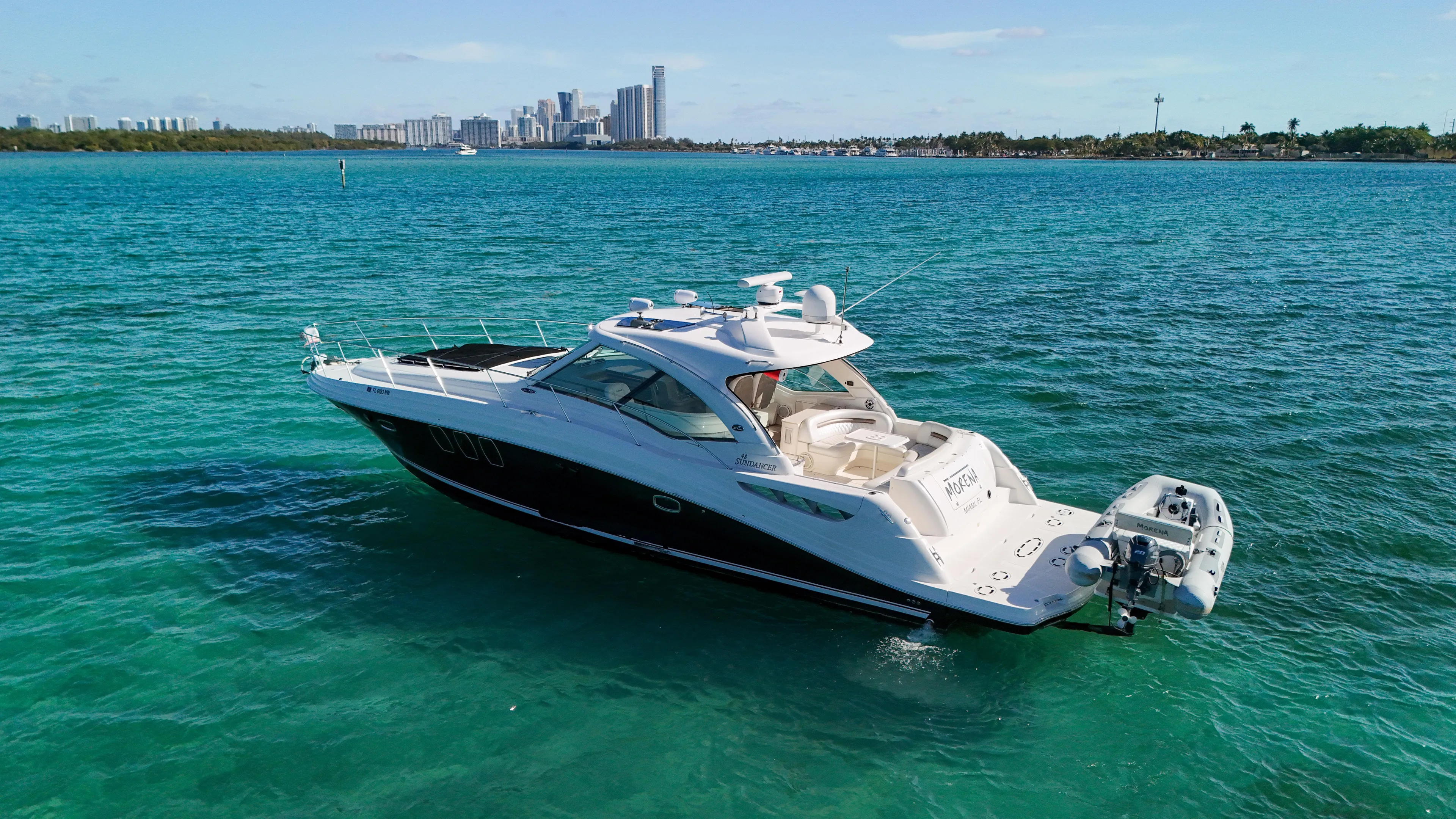 Morena Yacht Photos Pics 2008 Sea Ray 48 Sundancer yacht cruising on turquoise waters near a city skyline.