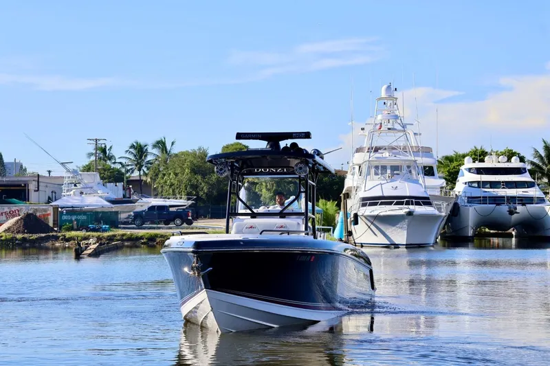  Yacht Photos Pics 2012 Donzi 38 ZF Open boat cruising in a marina with yachts in the background.