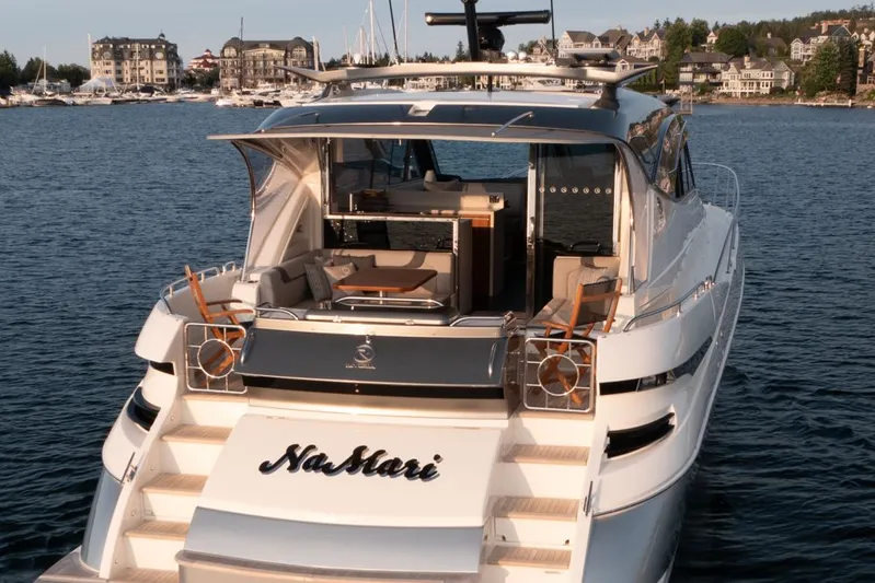 Namari Yacht Photos Pics 2022 Riviera 6000 Sport Yacht Platinum on water, luxury design, docked near coastal town.