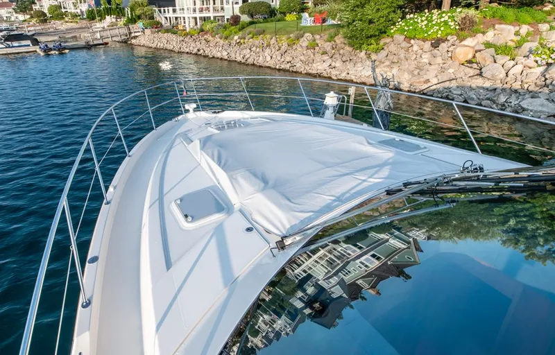 Namari Yacht Photos Pics 2022 Riviera 6000 Sport Yacht Platinum docked by rocky shoreline.