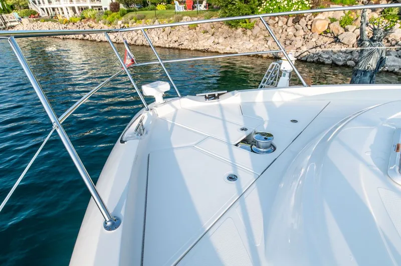 Namari Yacht Photos Pics Riviera 6000 Sport Yacht Platinum 2022 on water near rocky shoreline.