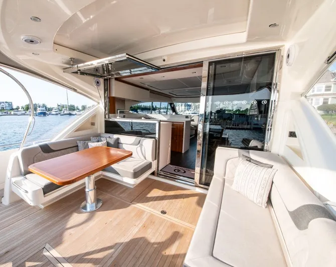 Namari Yacht Photos Pics 2022 Riviera 6000 Sport Yacht Platinum interior with elegant seating and wooden table.