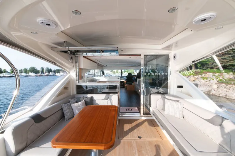 Namari Yacht Photos Pics Luxurious interior of 2022 Riviera 6000 Sport Yacht Platinum with elegant seating and wooden table.