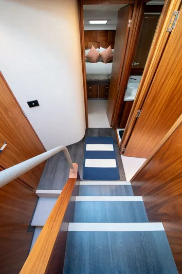 Namari Yacht Photos Pics Interior of 2022 Riviera 6000 Sport Yacht Platinum, featuring wooden stairs and cozy bedroom.