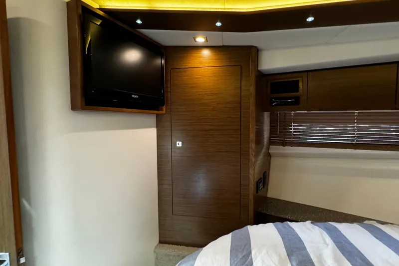  Yacht Photos Pics Interior of 2014 Cruisers Yachts 45 Cantius with TV, wood paneling, and striped bedding.