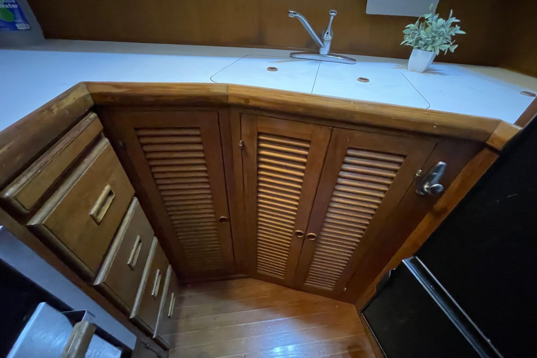 1986 NOVA MARINE 36 Sundeck kitchen with wooden cabinets and countertop sink.