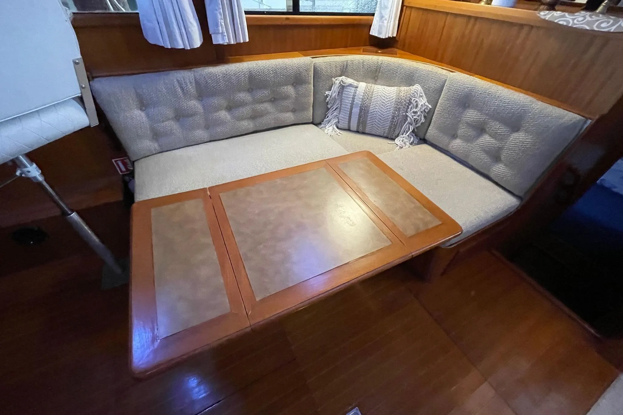 Cozy seating area on 1986 NOVA MARINE 36 Sundeck with cushioned bench and wooden table.