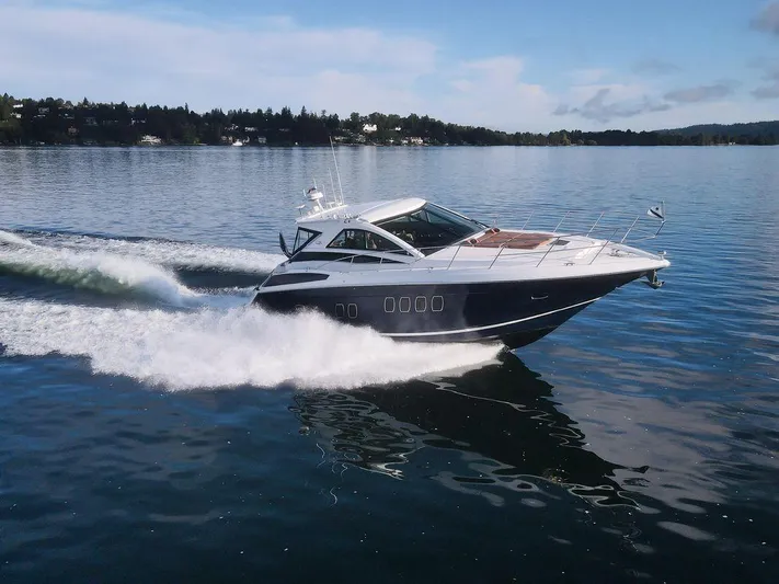 Blue Stiel Yacht Photos Pics 2009 Regal 52 Sport Coupe cruising on a calm lake under a clear blue sky.