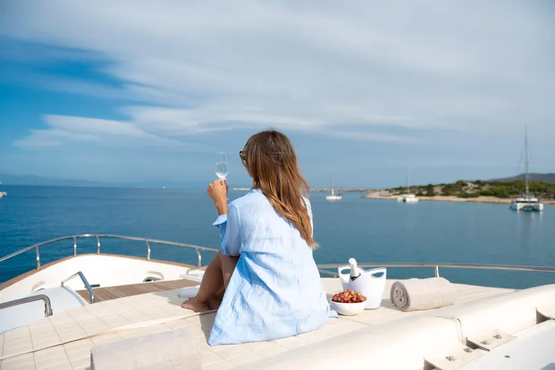 Red Rose Yacht Photos Pics Woman relaxing on Aicon 85 yacht, enjoying ocean view with wine and grapes.