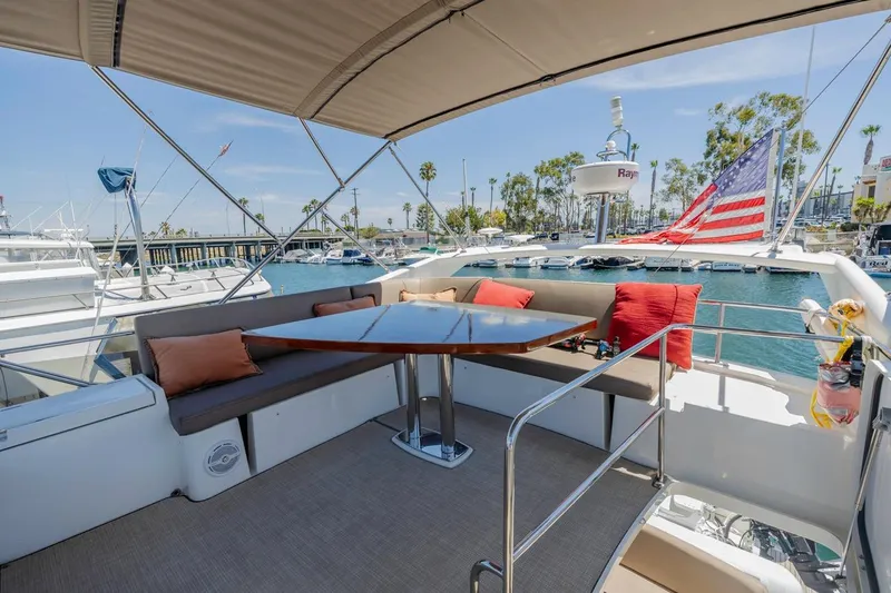 Shanti Yacht Photos Pics Flybridge of 2015 Prestige 500FB yacht with seating, table, and American flag in marina.