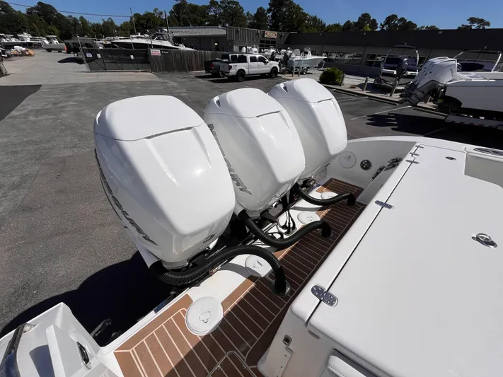  Yacht Photos Pics Triple outboard engines on a 2021 Fountain 38 SFC boat in a marina setting.