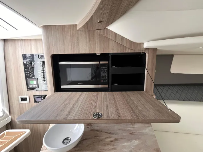  Yacht Photos Pics 2021 Fountain 38 SFC interior with microwave, wooden cabinetry, and modern design elements.