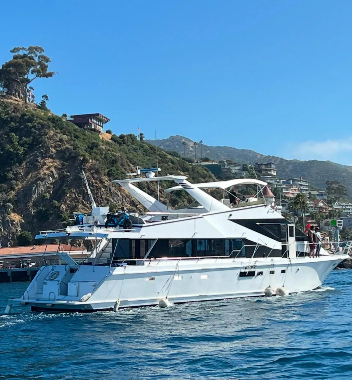 Custom 1989 yacht cruising near scenic coastal cliffs and lush greenery.