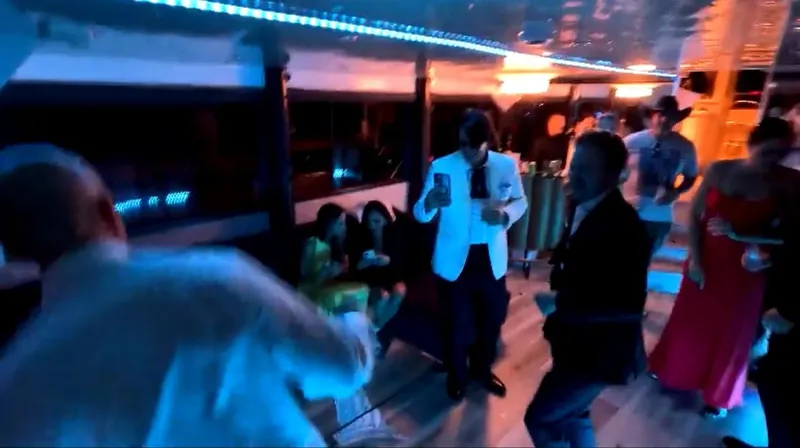 Scherzo Yacht Photos Pics People dancing and socializing in a dimly lit party bus with blue lighting.