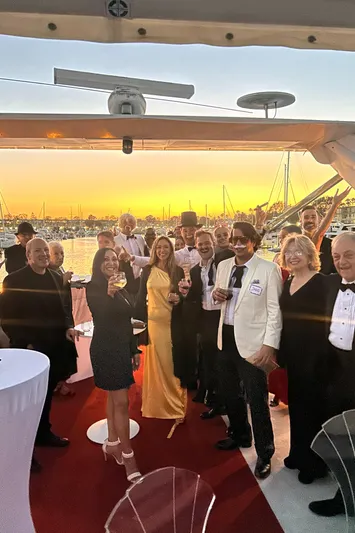 Scherzo Yacht Photos Pics Group celebrating on a yacht at sunset, dressed in formal attire.