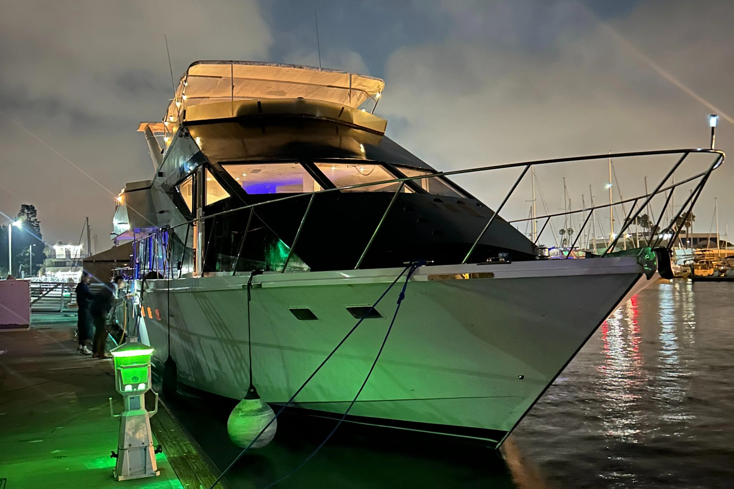 Luxurious 1989 custom yacht docked at night, illuminated by green lights.