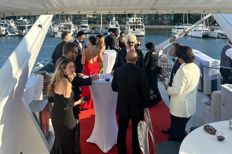 Scherzo Yacht Photos Pics Elegant yacht party with guests in formal attire, red carpet, and marina backdrop.