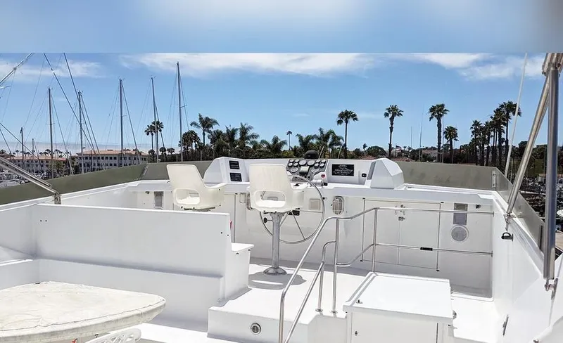 Scherzo Yacht Photos Pics Flybridge of a 1989 custom yacht with white seating and control panel, docked near palm trees.