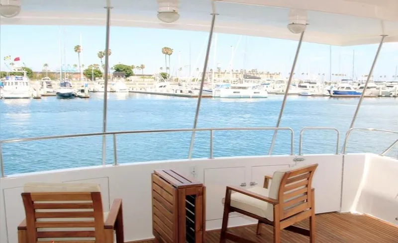 Scherzo Yacht Photos Pics View from a 1989 custom boat deck overlooking a marina with wooden chairs and calm waters.