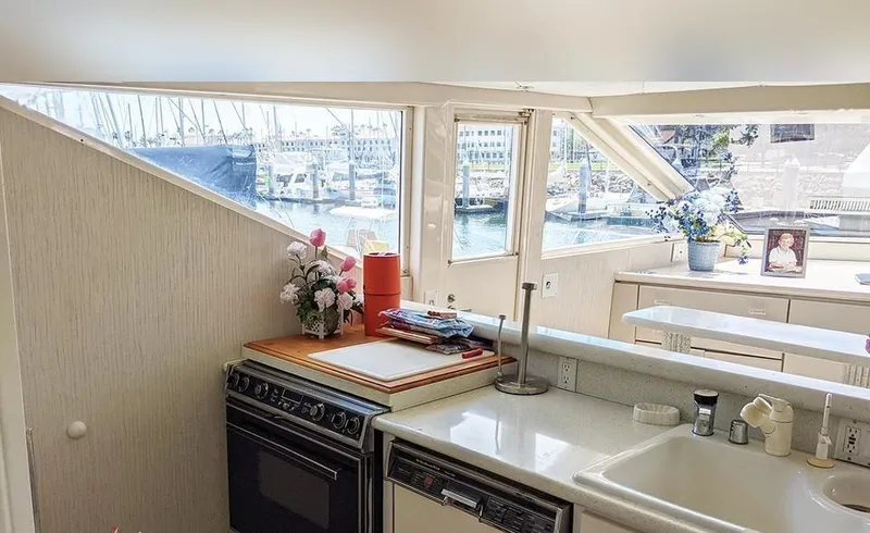 Scherzo Yacht Photos Pics Interior of a 1989 custom boat kitchen with stove, sink, and waterfront view.