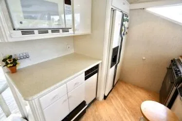 Scherzo Yacht Photos Pics Compact 1989 custom kitchen with white cabinets, modern appliances, and light wood flooring.