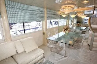 Scherzo Yacht Photos Pics Luxurious yacht interior with glass dining table, plush seating, and elegant chandeliers, 1989 custom model.