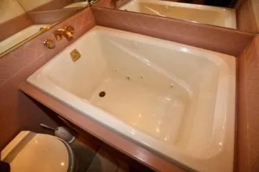 Scherzo Yacht Photos Pics Large white bathtub with gold fixtures, pink tile surround, and adjacent toilet, custom 1989 design.